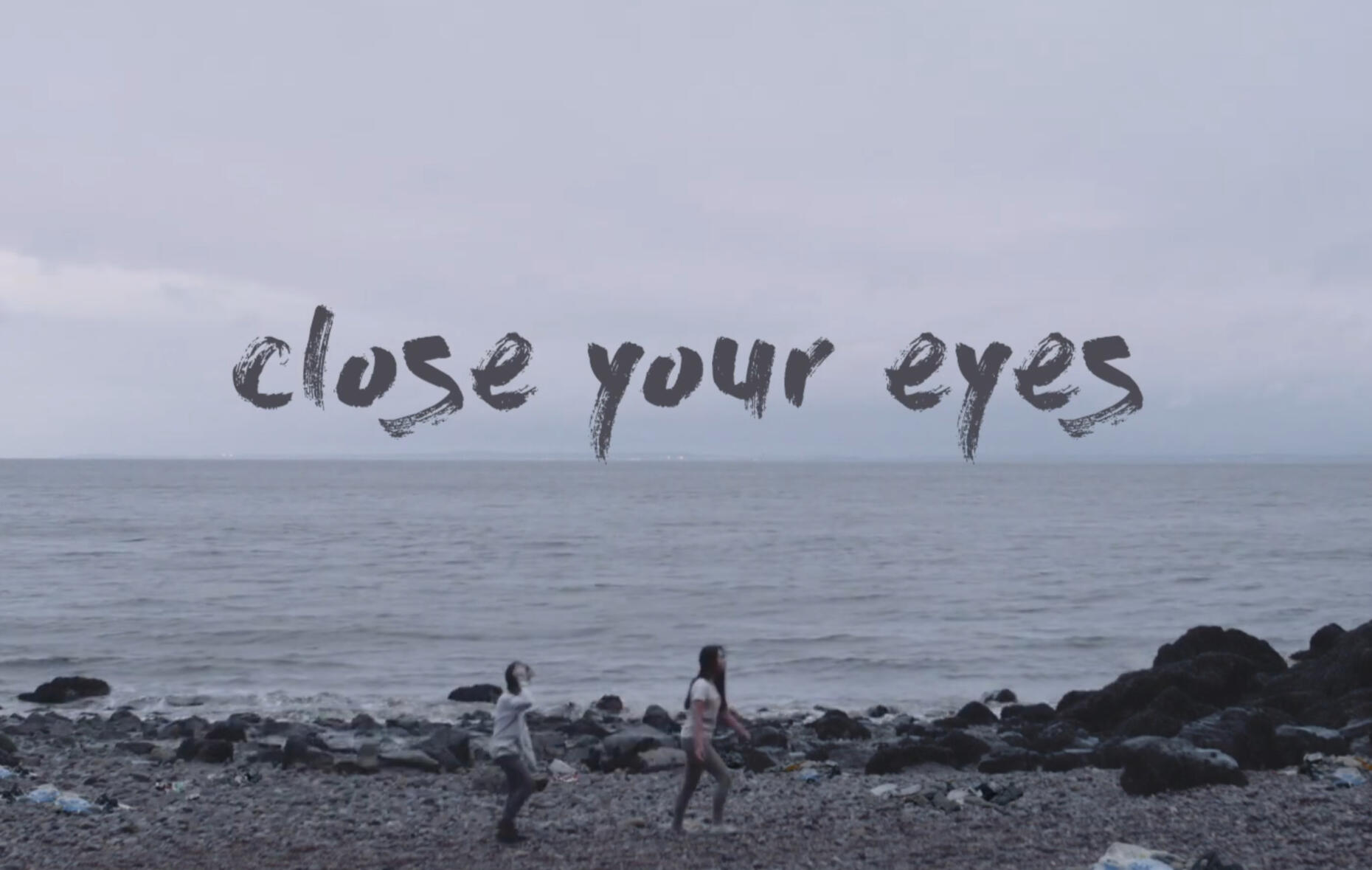 Two children walk across a heavily littered beach. Text that reads "close your eyes".